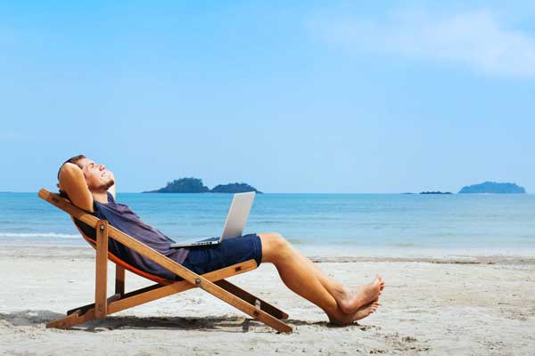 man happy with laptop on beach